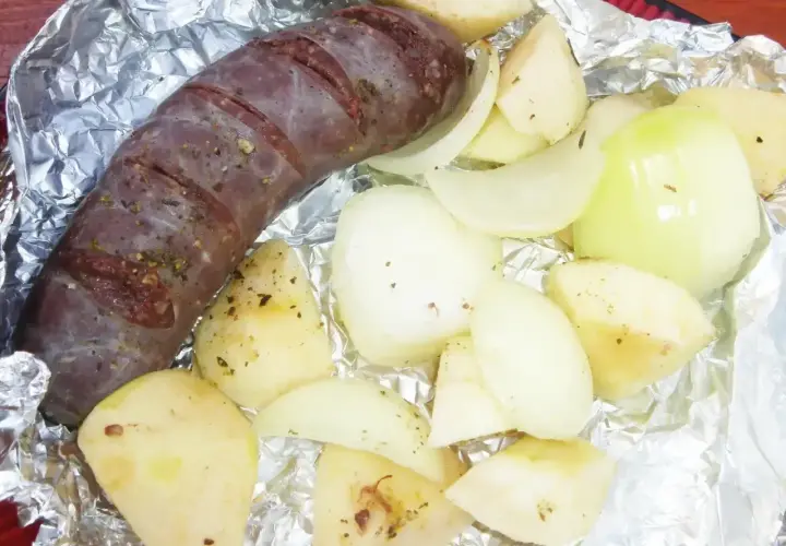 Kaszanka z grilla z cebulą w folii aluminiowej, gotowa do pieczenia. Aromatyczne dodatki podkreślą smak.