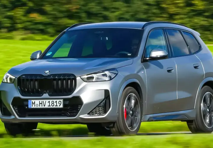 Grauer BMW X1 xDrive23d fährt auf einer grünen Wiese. Keine Probleme sichtbar, nur Fahrspaß.