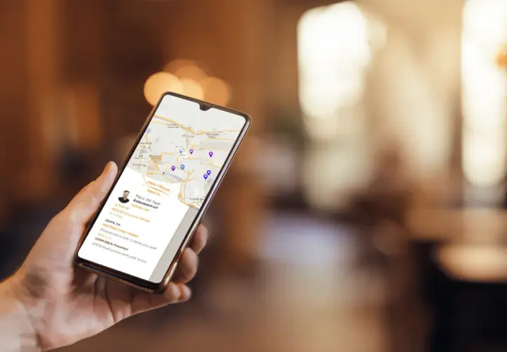Dłoń trzyma smartfon z mapą i danymi firmy. Czy wizytówka Google jest płatna? Nie, jest darmowa, co widać na ekranie.