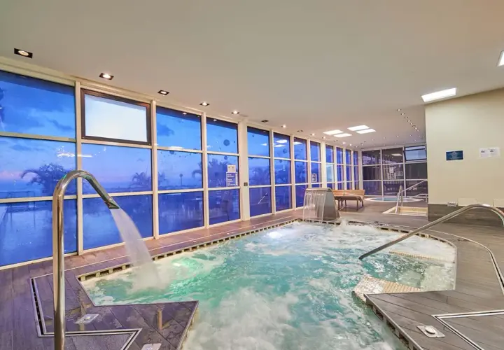 Piscina interior con ventanas azules que reflejan el cielo, cascadas y chorros de agua. Un lugar perfecto para relajarse, como si estuvieras en un spa de tui blue los gigantes.