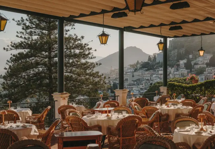 Terrazza con tavoli apparecchiati e vista su Taormina. Un luogo perfetto per un aperitivo al bar Timeo Taormina.