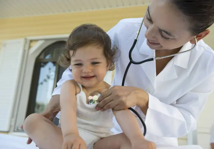 Medico ascolta il cuore di un bambino con uno stetoscopio. Un soffio al cuore cos'è? La visita medica rassicura.