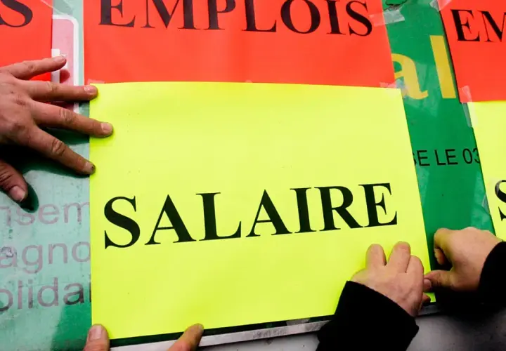 Ręce przyklejają plakaty z napisem "SALAIRE" (płaca). Ludzie walczą o najlepsze zarobki w Europie.