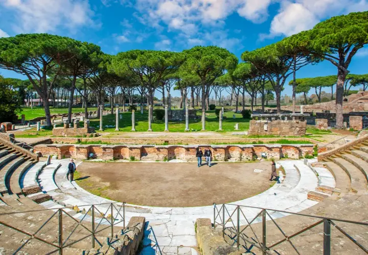 Antico teatro romano a Ostia Antica, Roma, con pini marittimi che incorniciano le rovine.