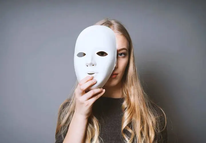 Ragazza bionda con maschera bianca, un'espressione che evoca il disturbo istrionico di personalità.