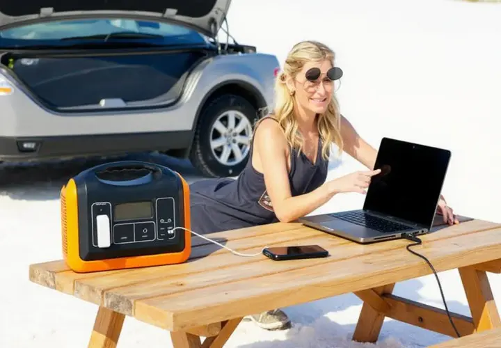 Femme travaillant sur son ordinateur portable, alimenté par un convertisseur 12 volts 220 volts camping car, près d'une voiture.