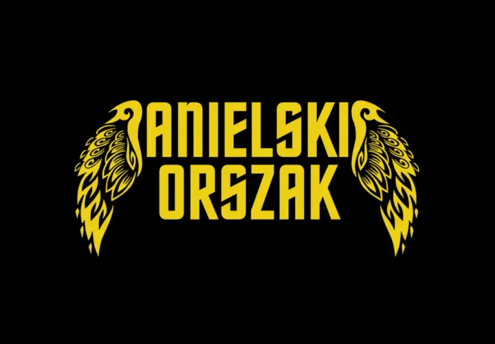 Żółty napis "ANIELSKI ORSZAK" z ozdobnymi skrzydłami po bokach, na czarnym tle.