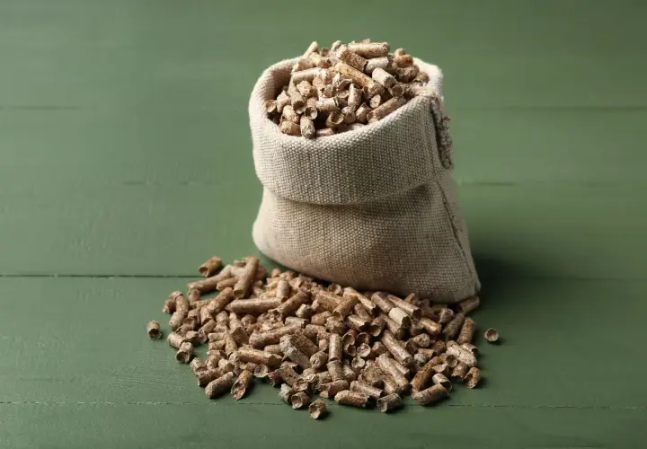 Worek z pelletem na zielonym tle. Zastanawiasz się, ile waży worek pelletu?