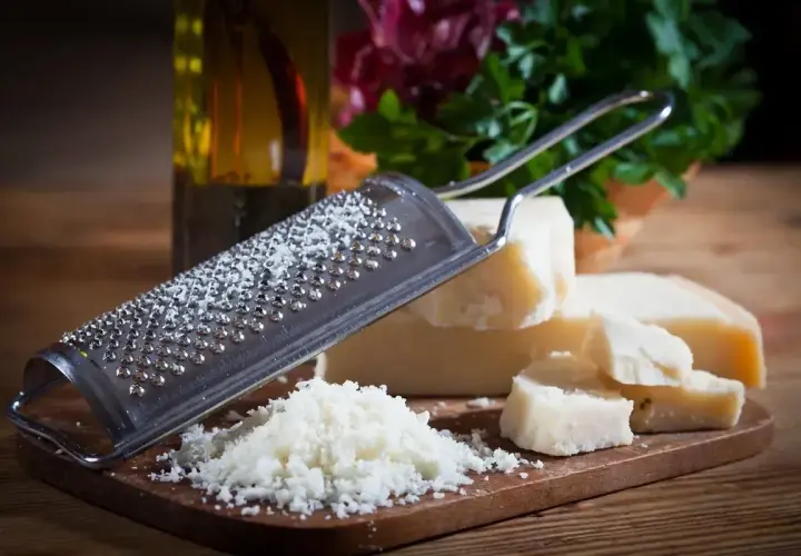Tarka z grudkami sera, obok kawałki Grana Padano i parmezanu, gotowe do starcia.