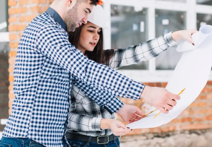 Pareja revisa planos de construcción. Saben qué se necesita para tasar una vivienda, analizando cada detalle.