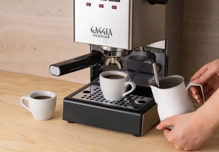Jaka kawa do ekspresu kolbowego? Świeżo zaparzony espresso w filiżance, obok dzbanek do mleka.