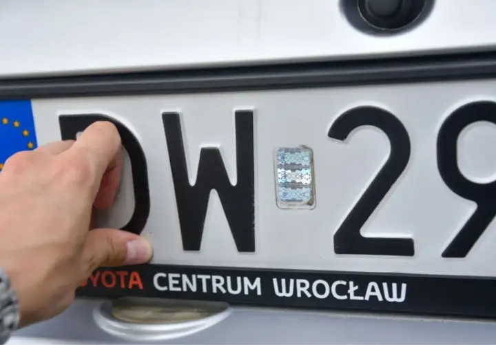 Ręka dotyka litery D na tablicy rejestracyjnej DW 29. Tst rejestracja w Toyota Centrum Wrocław.