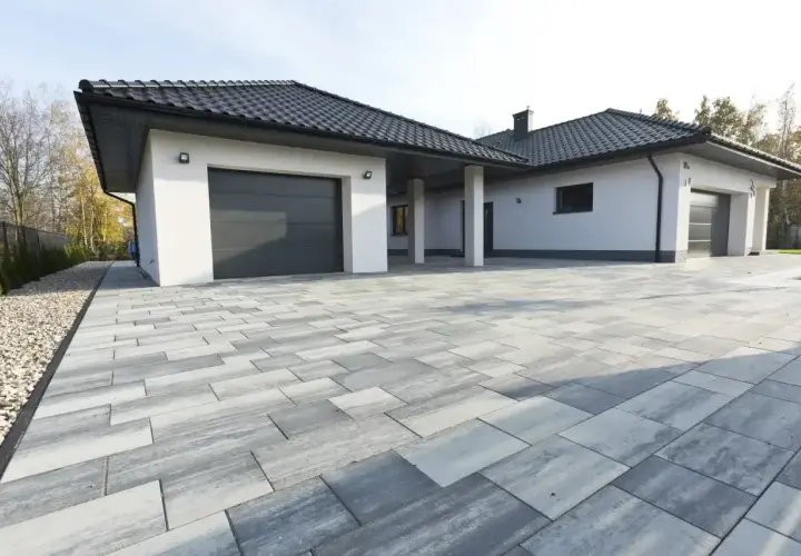 Nowoczesny podjazd z kostki brukowej w odcieniach szarości, idealne podjazd z kruszywa inspiracje. Elegancki dom z dwoma garażami.