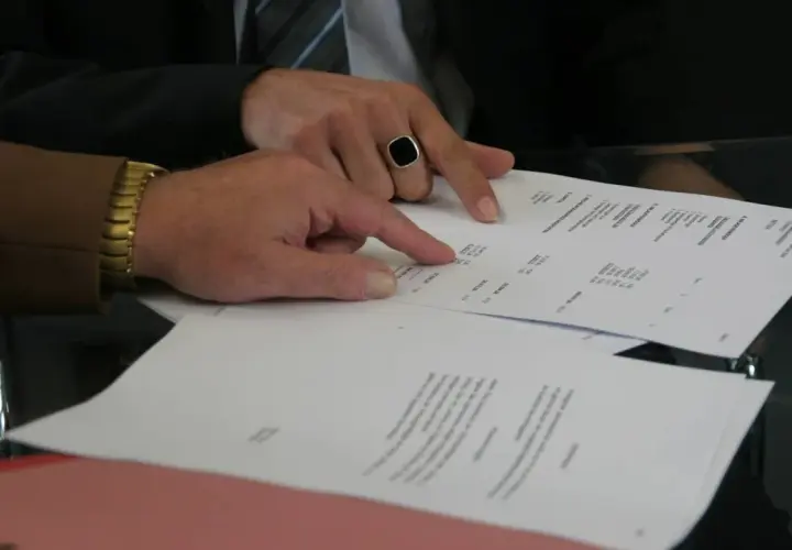 Dwaj mężczyźni analizują dokumenty, jeden wskazuje palcem na wypowiedzenie umowy najmu wzór przez wynajmującego.