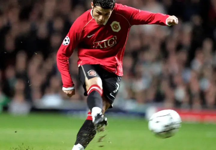 Cristiano Ronaldo w czerwonej koszulce Manchesteru United, z numerem na koszulce, kopie piłkę.