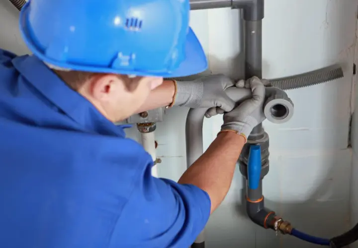 Instalator montuje odpowietrzenie kanału sanitarnego w domu parterowym, łącząc rury.