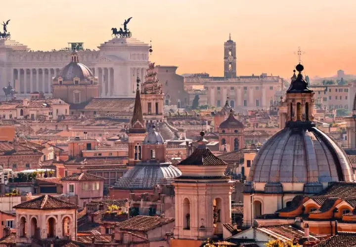 Panorama di Roma al tramonto, con cupole e monumenti iconici. Un invito a scoprire le tante cose da fare a Roma.