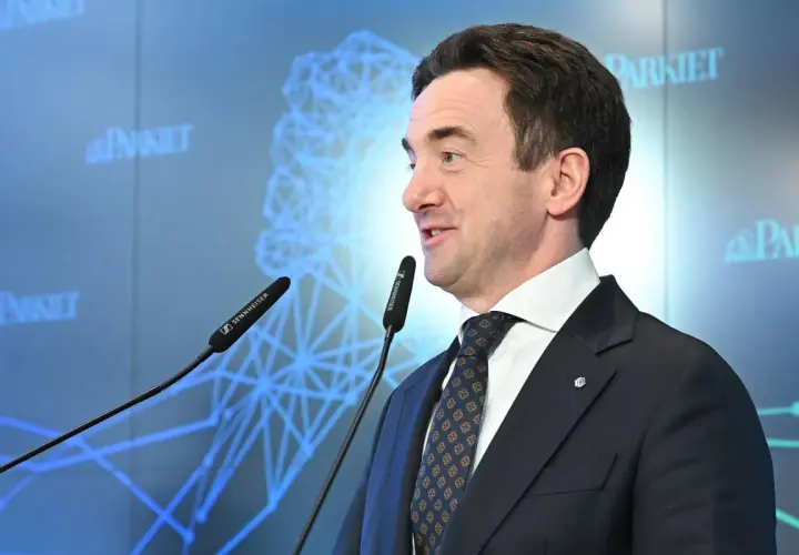 Mężczyzna w garniturze przemawia przy mikrofonach. Na ekranie w tle logo "Parkiet" i schemat sieci. Giełda Papierów Wartościowych (GPW) i bankierzy dyskutują o przyszłości.