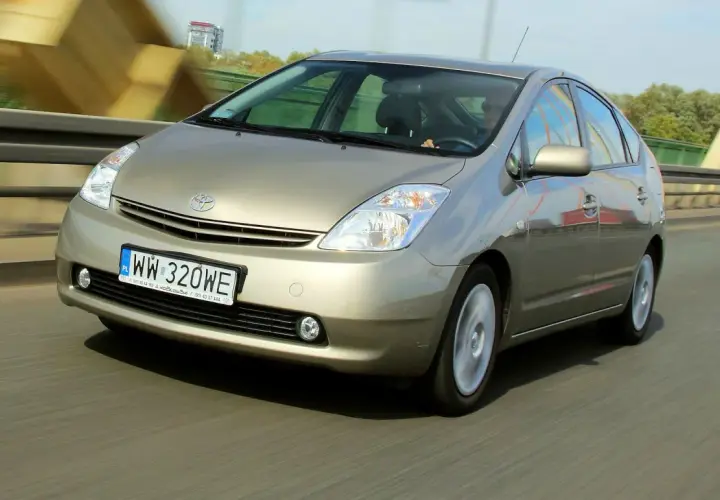 Złoty Toyota Prius 2 jedzie po moście, rejestracja WW 320WE.