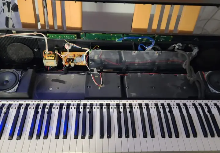 Wnętrze keyboardu podczas naprawy instrumentów muzycznych. Widoczne głośniki, płytki drukowane i okablowanie.