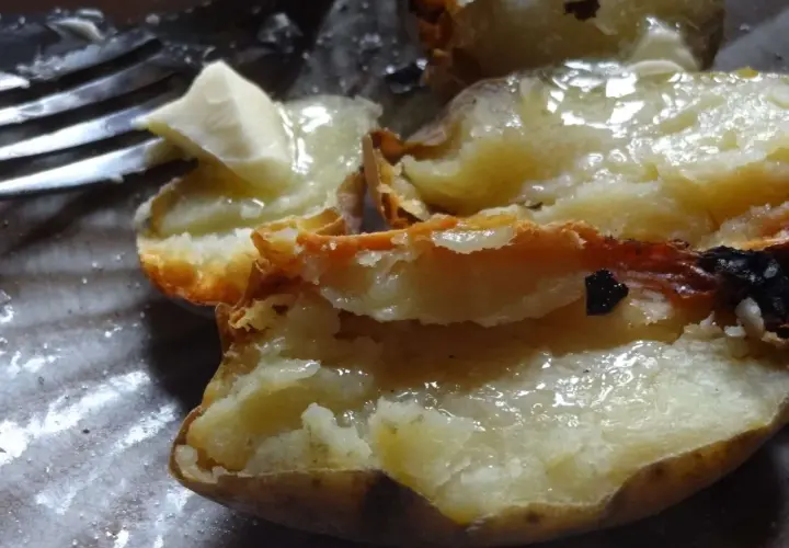 Pommes de terre cuites dans la cendre, ouvertes et garnies de beurre fondant. Un délice simple.