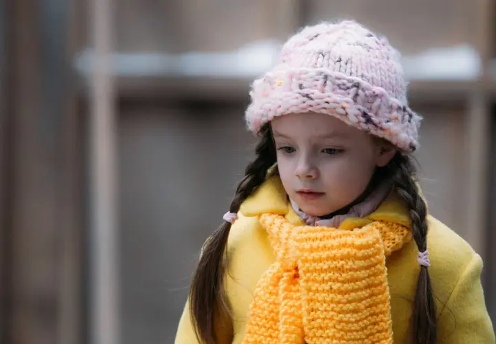 Smutna dziewczynka w żółtym płaszczu i różowej czapce, jak z serialu "Ukochane dziecko".