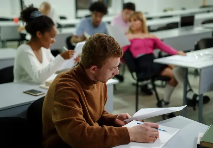 Studenci w sali wykładowej, skupieni na nauce. Nawet bez matury można rozpocząć studia, zdobywając wiedzę i nowe umiejętności.