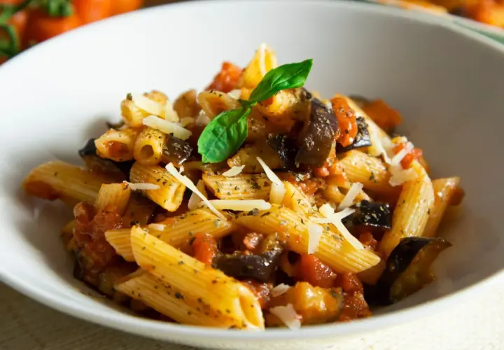 Penne z bakłażanem i pomidorami, posypane parmezanem. Proste danie włoskie, które zachwyca smakiem.