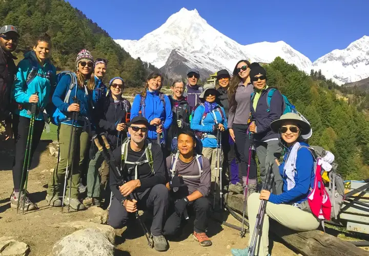 Grupa turystów na tle ośnieżonych gór podczas Manaslu Circuit Trek. Wszyscy uśmiechnięci, gotowi na przygodę.
