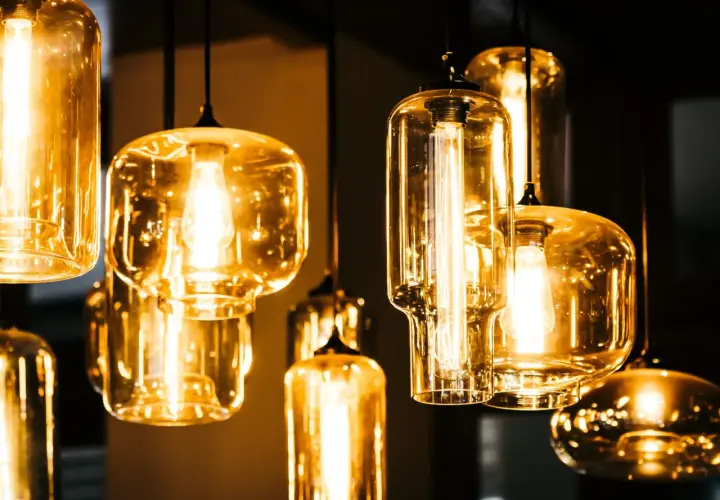 Jak czyścić szklany klosz lampy? Kilka wiszących lamp z bursztynowymi kloszami i widocznymi żarówkami.