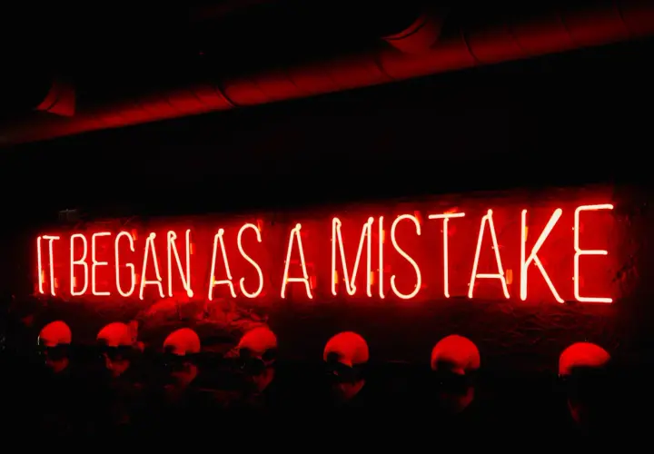 Neon rosso "IT BEGAN AS A MISTAKE" sopra teschi. Come si dice "lunedì" in inglese? Monday.