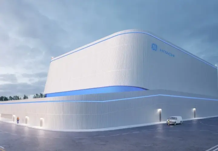 Nowoczesny budynek z logo GE Hitachi, prawdopodobnie elektrownia jądrowa BWRX-300, z niebieskimi akcentami świetlnymi.