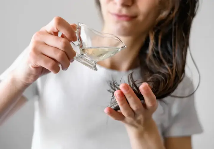 Kobieta aplikuje hydrolat na końcówki włosów. Hydrolat co to? To woda kwiatowa, która nawilża i odżywia włosy.