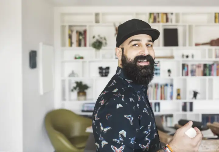 Ein lächelnder Mann mit Bart und Kappe, der als creative director neue Ideen entwickelt.