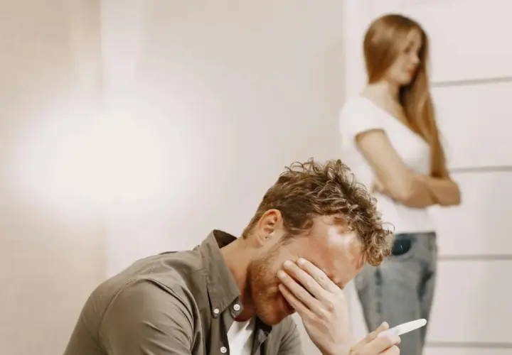 Uomo disperato con test di gravidanza in mano, mentre una donna si volta. Un esempio di uomini che non sanno stare in una relazione.