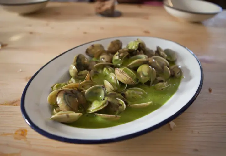 Plato de almejas en salsa verde, un manjar marino bañado en una vibrante y sabrosa salsa.