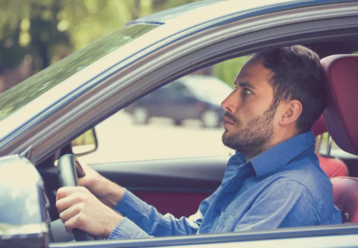 Uomo con espressione tesa al volante, forse a causa della paura di guidare.