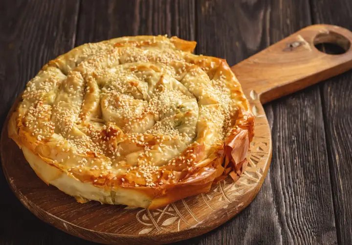 Burek al formaggio, una torta salata a spirale con semi di sesamo, pronta per essere gustata.