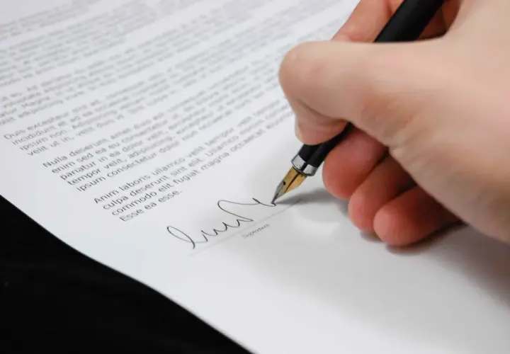 Mano firmando un documento con una pluma estilográfica, un paso clave para firmar contrato online.