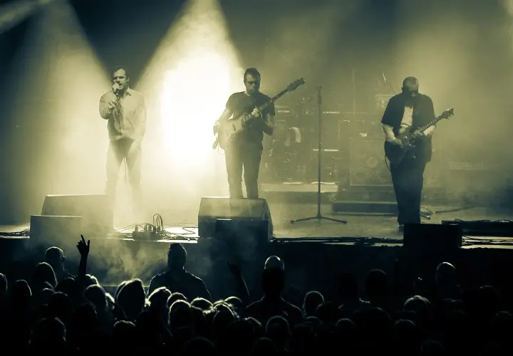 Koncert zespołu Coma z Leszkiem Żukowskim na wokalu. Muzycy na scenie, w tle dym i światła. Publiczność w pierwszym planie.