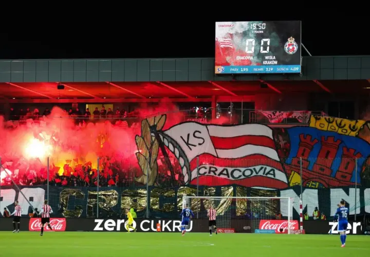 Oprawa kibiców najstarszego klubu piłkarskiego w Polsce, Cracovii, z racami i transparentami. Na tablicy wyników 0:0.