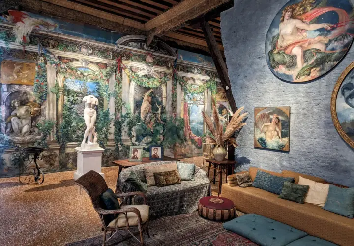 Intérieur du museo Fortuny, avec une statue antique, des peintures murales luxuriantes et des meubles confortables.