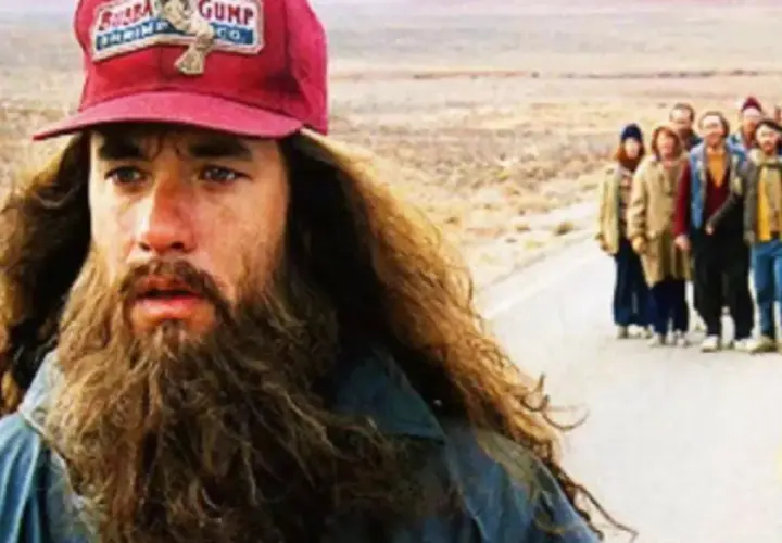 Forrest Gump (Tom Hanks) z brodą i czapką "Bubba Gump Shrimp Co." prowadzi grupę ludzi w podróży. Forrest Gump obsada w akcji.