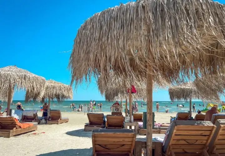 Słoneczny dzień na plaży w Rumunii nad Morzem Czarnym. Leżaki pod strzechą czekają na plażowiczów.