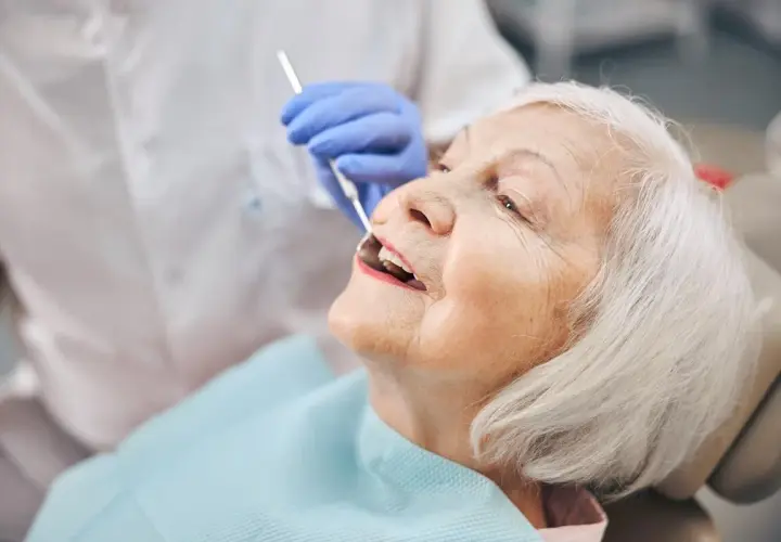 Starsza pani u dentysty, która właśnie otrzymała protezę akronową.