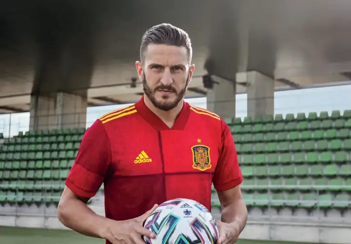 Piłkarz w czerwonej koszulce Hiszpanii z piłką, gotowy do gry w stylu tiki-taka.