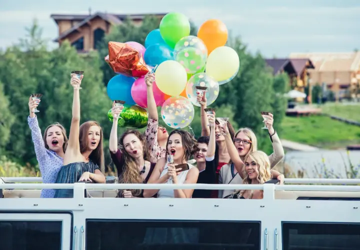 Radosne kobiety z kieliszkami i balonami świętują wieczór panieński.