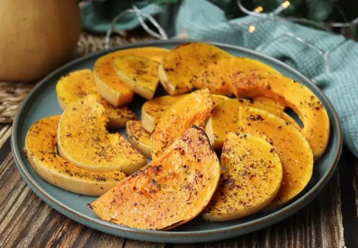 Rodajas de calabaza a la plancha, doradas y sazonadas con hierbas, servidas en un plato azul.
