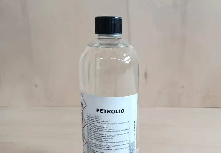 Bottiglia di **petrolio bianco su legno**. Liquido infiammabile, da usare con cautela.
