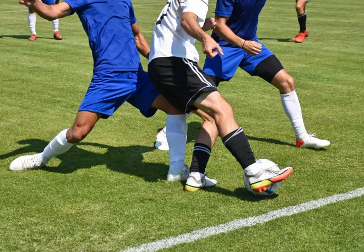 Piłkarze w akcji, jeden próbuje odebrać piłkę, pokazując skuteczną grę defensywną.